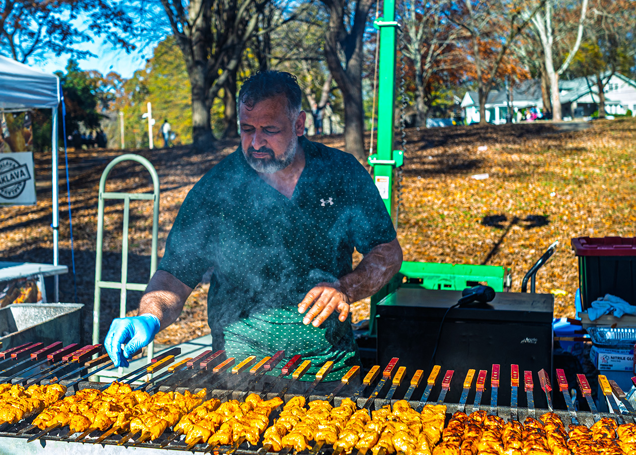 Man grilling rows of halal chicken skewers at Halal Fest 2025 in Atlanta